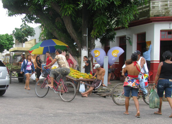 2-bikes-and-peds-pass-fruit-stand_7048 Bikes turn the corner in front of street vendor in Icoaraci.