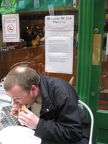 eating-under-starvation-sign_8183 Sign about famine in Zimbabwe, part of the a Nutopia exploring adventure, on window behind the guy and his sandwich.