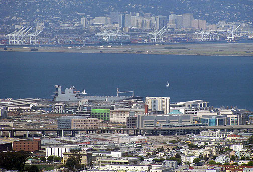 mission-bay-w-oakland-port-behind_9958 From Twin Peaks you can see two dominant industries that straddle the Bay: past the freeway the new office buildings make up UCSF Mission Bay, a biotech campus, and across the bay is the abandoned Alameda Naval Air Station with the many cranes that dominate the Port of Oakland and have been the linchpin of globalization.