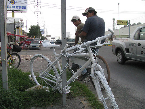 ghost-bike-w-two-guys-passing-on-bike-and-traffic_2229 Two workers going home on bike pass a just-installed Ghost Bike.