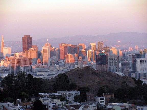Sunset view from Tank Hill, sun lighting up windows in east bay hills, Corona Heights in foreground.